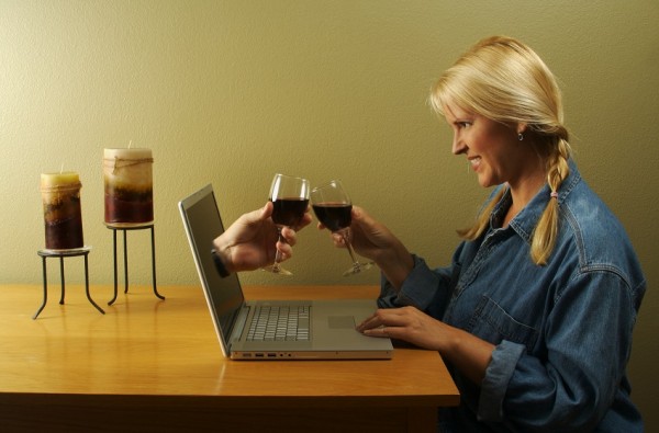 Online dating concept. Hand & Wine Glass Through Laptop Screen