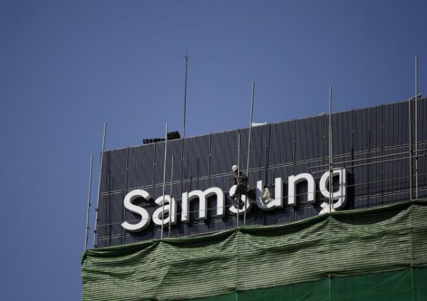 A worker works on a Samsung outdoor advertisement installed atop an office building in central Seoul