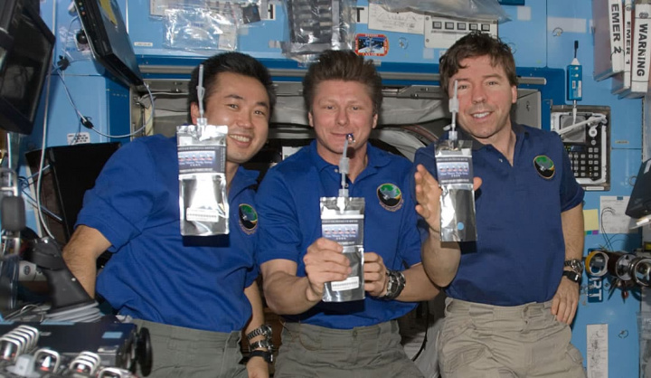 Imagem de astronautas a beber água reciclada na Estação Espacial Internacional