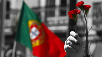 Imagem da bandeira de Portugal e os cravos vermelhos do 25 de abril