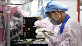 Imagem trabalhador da Foxconn a montar um iPhone 12