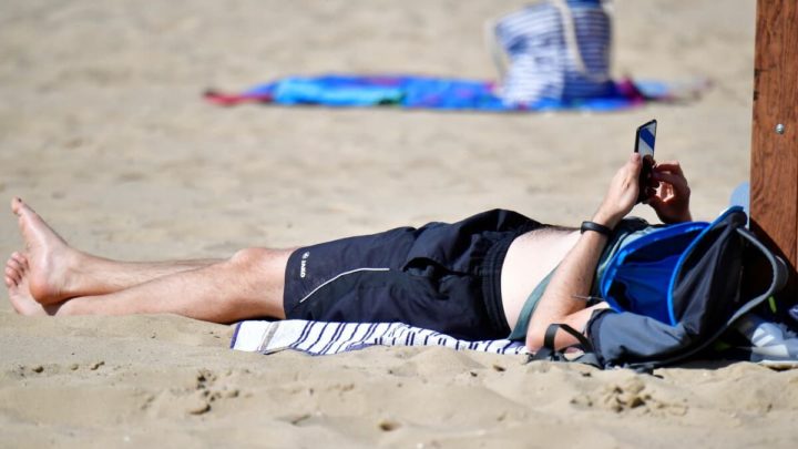 Homem na praia com o smartphone