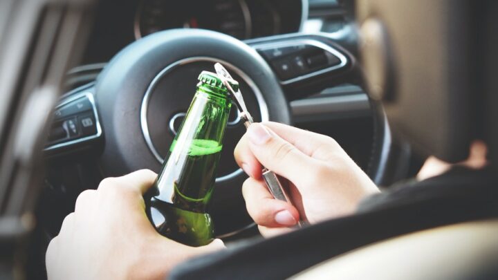 Condutor a abrir uma garrafa de cerveja, com álcool
