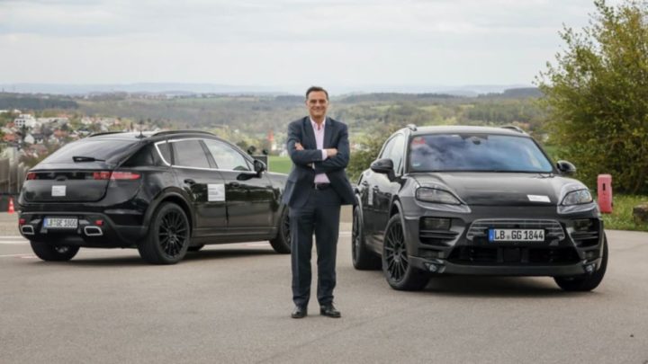 Michael Steiner, membro do Executive Board, Research and Development, da Porsche AG, em frente a dois protótipos camuflados do Porsche Macan 100% elétrico.