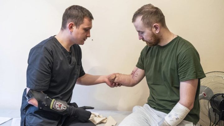 Alexis Cholas examina um soldado amputado, Volodymyr Symyshyn, no hospital em Kyiv, Ucrânia. Crédito: AP Photo/Evgeniy Maloletka