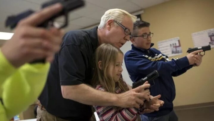O instrutor Jerry Kau mostra a um aluno como segurar uma arma de fogo durante uma aula de segurança para jovens com arma de fogo em East Dundee, Illinois, em 21 de abril de 2015. Fonte: Newsweek (Jim Young/ Reuters)