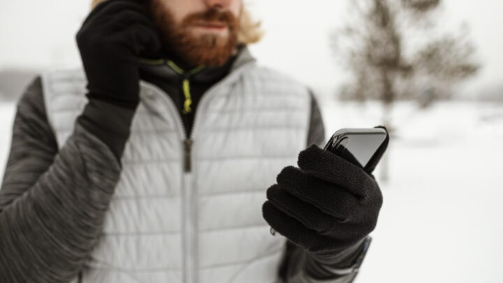 Homem a usar o smartphone no frio, com luvas