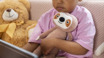 Criança com urso de peluche e tablet