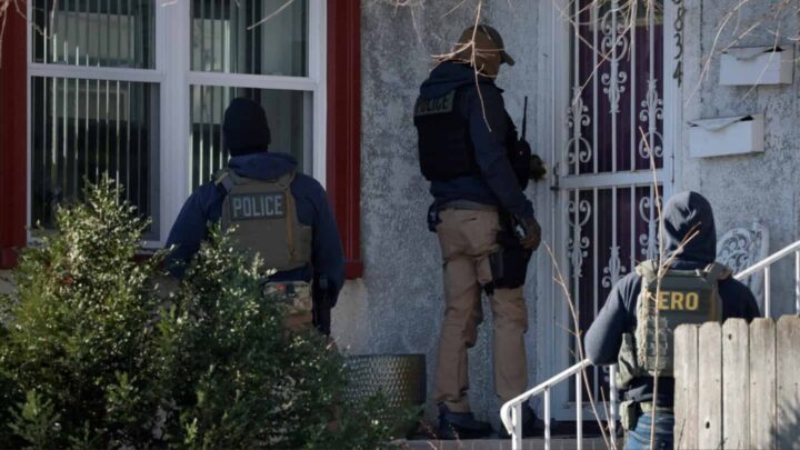 Agentes federais do ICE batem à porta de uma casa após os assassinatos de Renee Nicole Good e Alex Pretti por agentes federais de imigração em Minneapolis, no Minnesota, EUA, no dia 28 de janeiro de 2026. Crédito: Brian Snyder/Reuters, via <a href="https://www.pbs.org/newshour/politics/department-of-homeland-security-intensifies-surveillance-in-immigration-raids-sweeping-in-citizens">PBS</a>