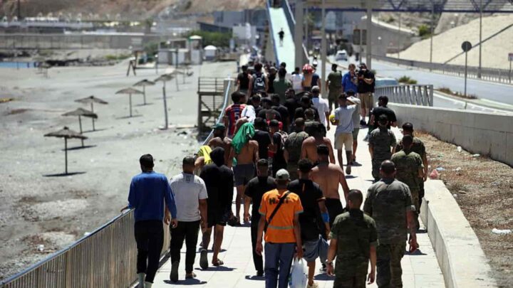 Um grupo de migrantes a aproximar-se da fronteira para regressar a Marrocos, escoltado por soldados espanhóis, em Ceuta, no dia 2 de agosto. Crédito: Henry Nicholls/AFP/Getty Images, via Bloomberg