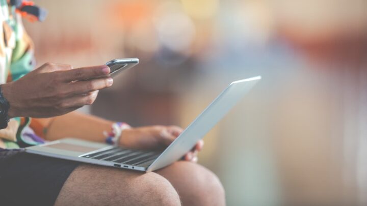 Pessoa a utilizar um smartphone e computador, a representar a utilização de Internet