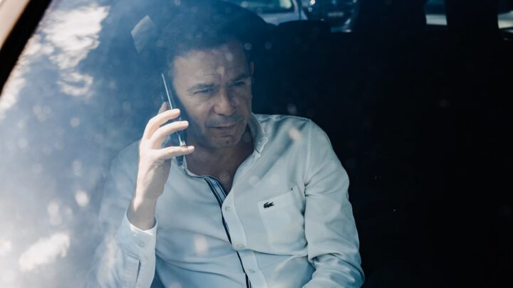 Primeiro-ministro português, Luís Montenegro, dentro de um carro, com o telemóvel na orelha.